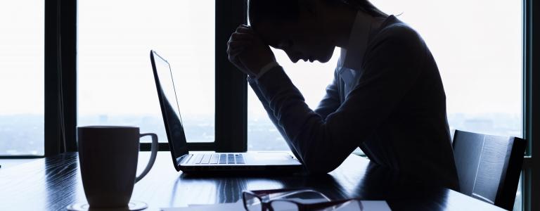 Femme devant son ordinateur se tenant la tête de tristesse. 