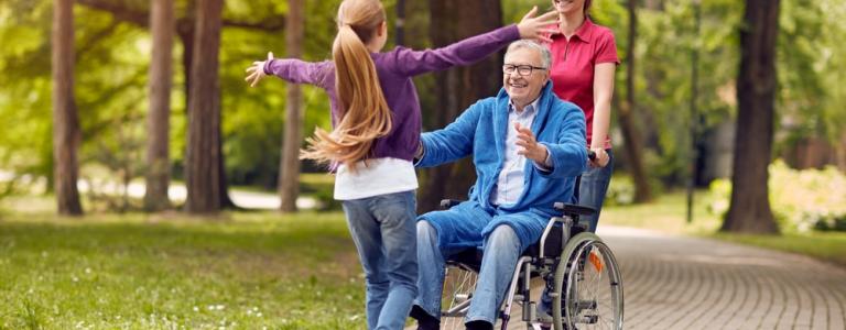 grand-père handicapé joyeux en fauteuil roulant accueillant sa petite-fille heureuse