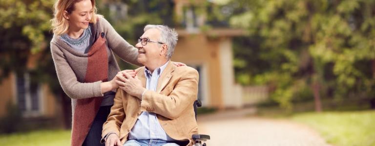 Homme âgé en fauteuil roulant avec fille soignante heureuse