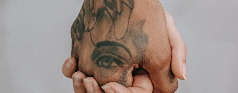 Deux mains enlacées, l'une est tatouée